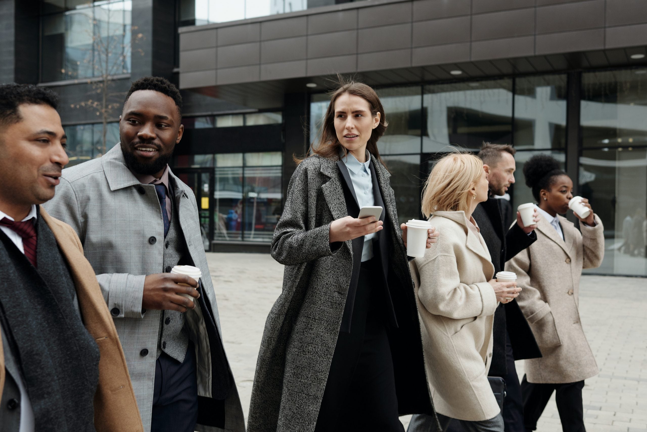 A group of workers walk to an office carrying coffee cups